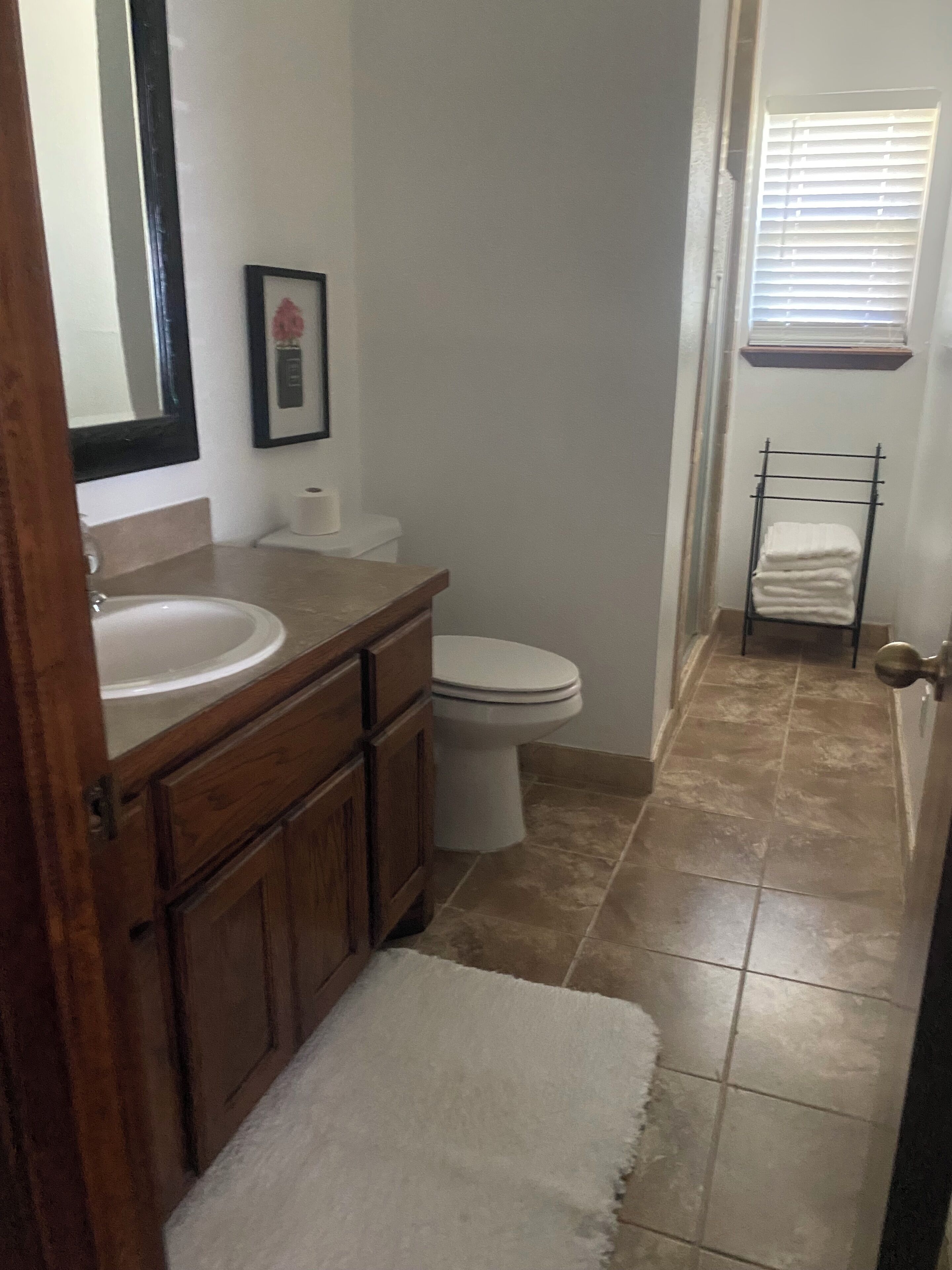 A bathroom with a wooden vanity, a white sink, a toilet, and a towel rack.