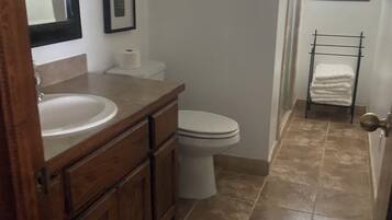 A bathroom with a wooden vanity, a white sink, a toilet, and a towel rack.