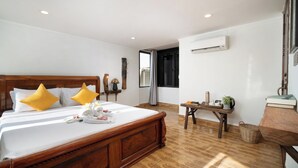 A neatly arranged bedroom with a wooden bed, a bedside table with a vase and a book, and a view of the outside through a window. - Stay Siem Reap (Siem Reap)
