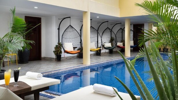 A pool area with lounge chairs, hanging chairs, and potted plants. - Stay Siem Reap (Siem Reap)