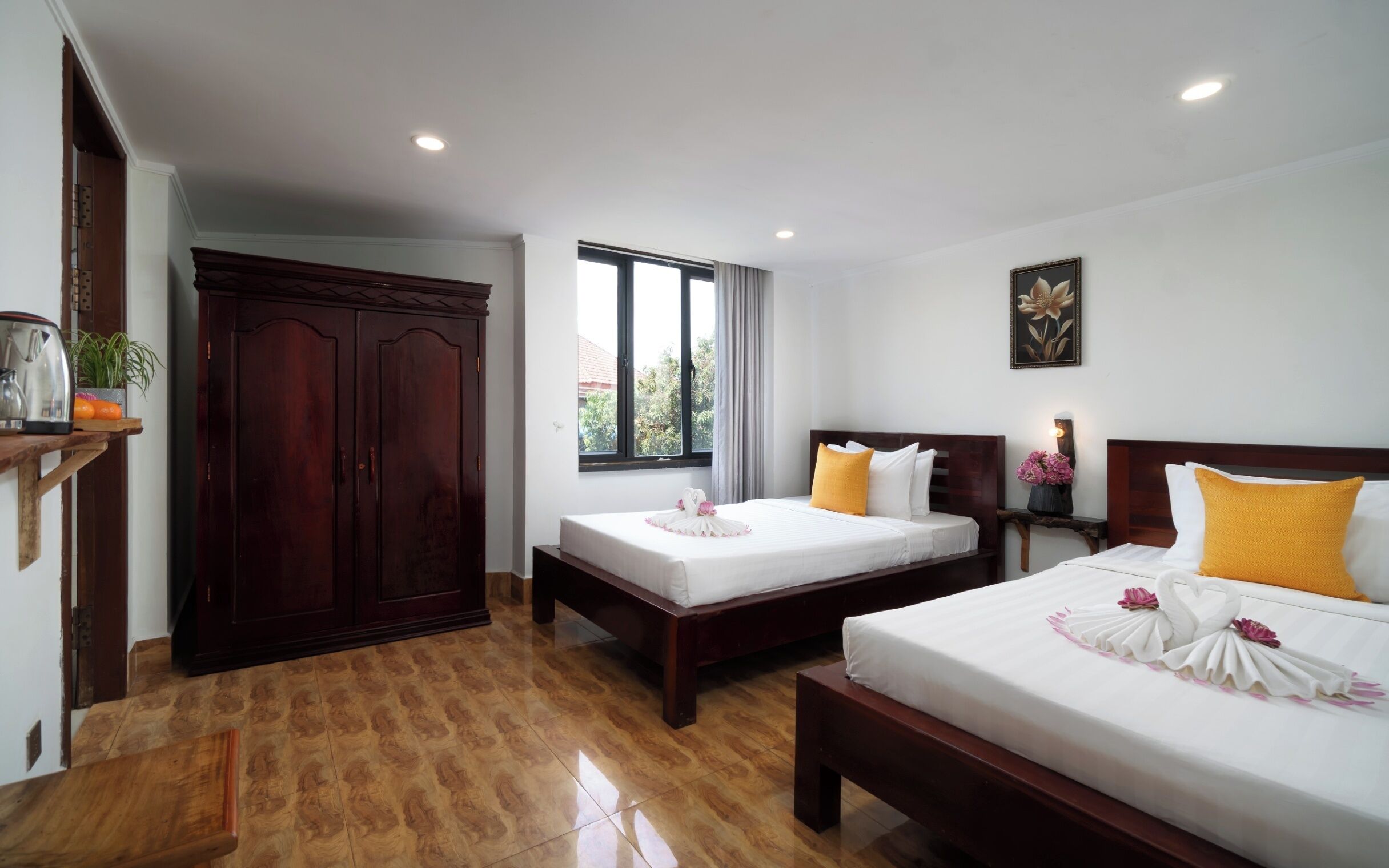 A hotel room with two single beds, a wardrobe, a window with a view, and a painting on the wall.