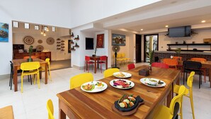 A spacious dining area with a wooden table set for a meal, surrounded by yellow chairs. - Stay Siem Reap (Siem Reap)