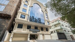 Un hotel con una amplia fachada de vidrio en arco, entrada a nivel de calle y un cartel en idioma extranjero.