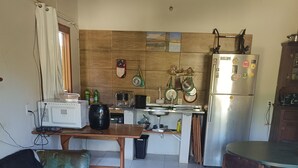 Um espaço compacto com cozinha compacta, cama com roupa de cama verde e área de refeições com mesa e cadeiras.
