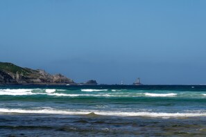 A coastal view with waves, a lighthouse, and rocky cliffs. - Seaside Escape in Audierne: Maritime-Themed Cottage at the Tip of Southern Finistère (Audierne)