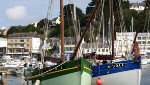 A harbor with boats docked, a pier, and buildings in the background. - Seaside Escape in Audierne: Maritime-Themed Cottage at the Tip of Southern Finistère (Audierne)