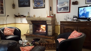 A cozy living room with a fireplace, leather chairs, a television, and various decorative items. - Seaside Escape in Audierne: Maritime-Themed Cottage at the Tip of Southern Finistère (Audierne)