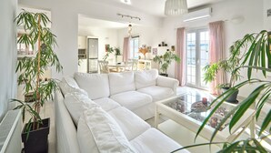 A modern living room with a white sofa, a glass coffee table, and potted plants. - La Belle Casa de Parikia (Paros)