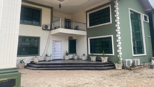 A two-story building with a balcony, large windows, and potted plants. - Room-flexible 8-bedroom Luxury Apartment (Benin City)