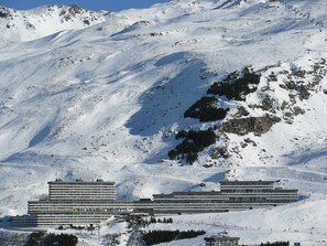 A large hotel with multiple floors and a ski resort in the background.