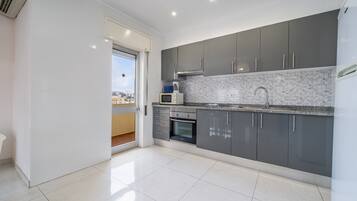 A modern kitchen with grey cabinets, a tiled backsplash, and a built-in oven.