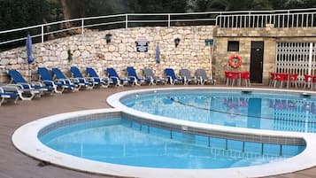 A swimming pool with lounge chairs and a stone wall.