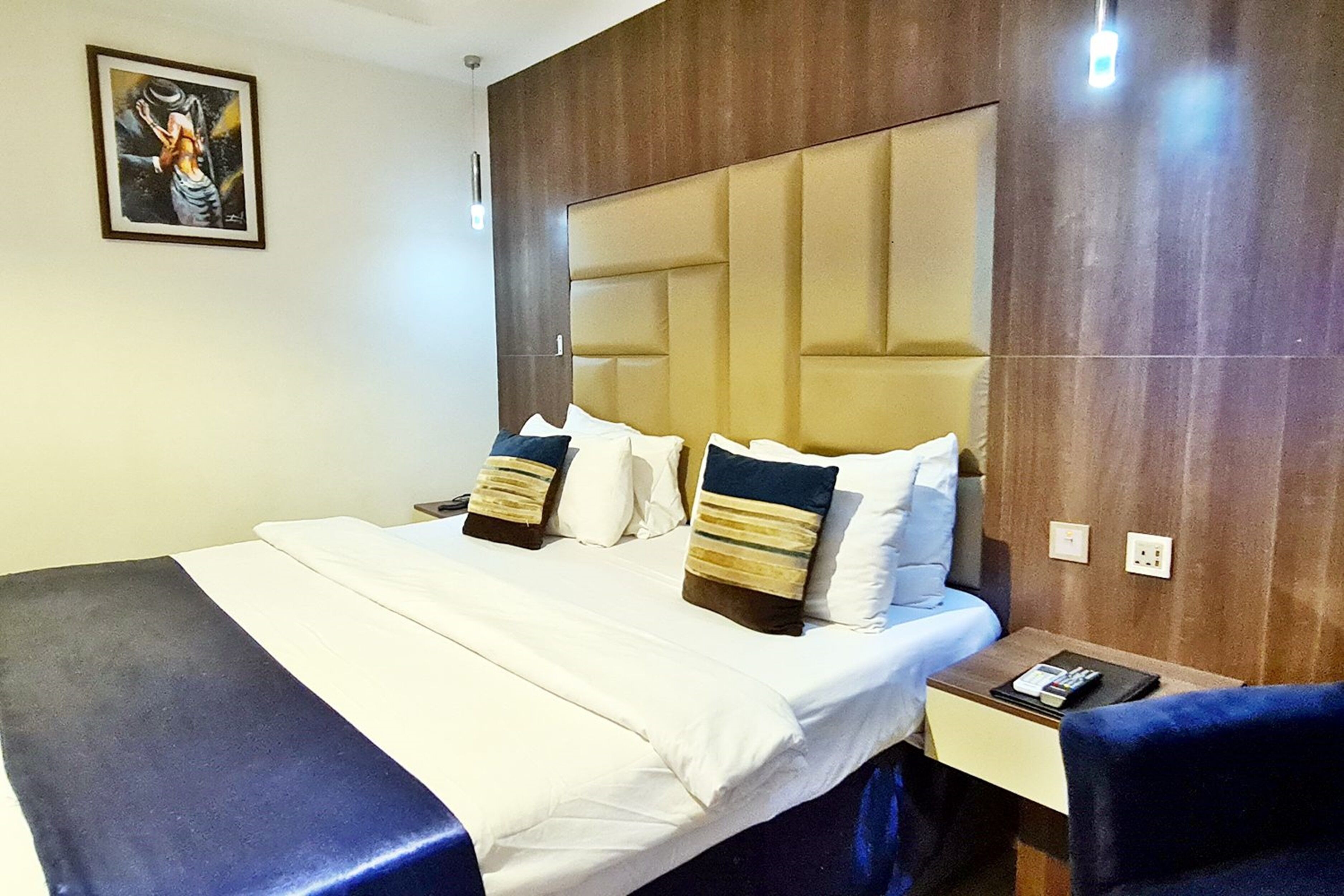 Una habitación de hotel con una cama grande, un cabecero, una mesita de noche y una silla.