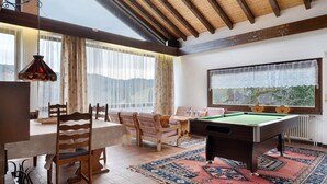 A room with a pool table, wooden chairs, a dining table, and a large window with a view. - Apartment with Mountain View Steinbühl 4 with Private Terrace and Balcony (Wieden)