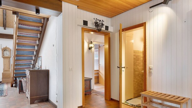 A staircase with patterned rugs, a wooden bench, and a hallway leading to a door. - Apartment with Mountain View Steinbühl 4 with Private Terrace and Balcony (Wieden)