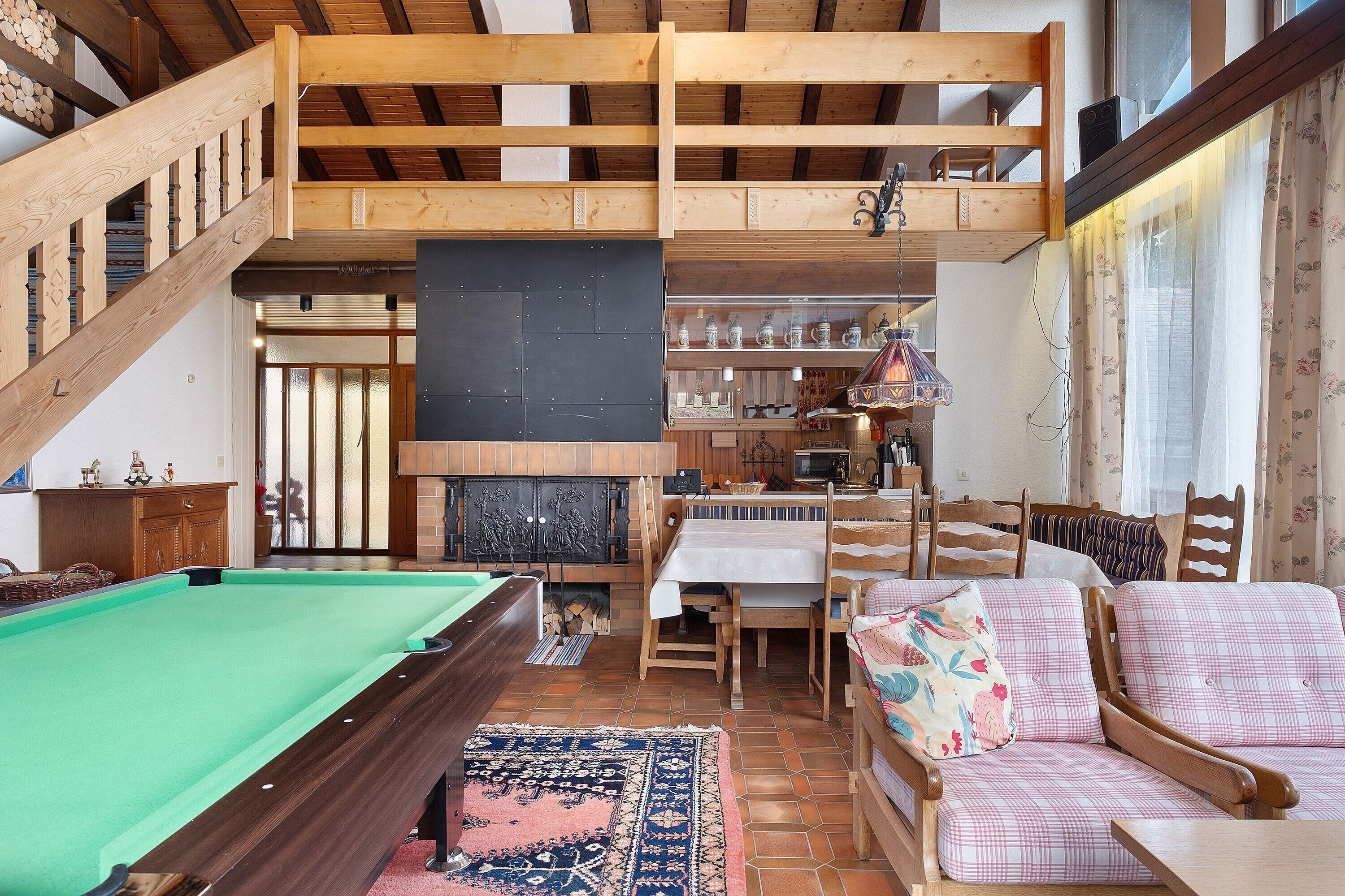Een houten interieur met een pooltafel, een bank en een eethoek.