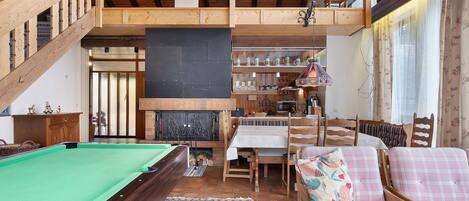 A wooden interior with a pool table, a sofa, and a dining area.