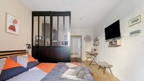 Ein Schlafzimmer mit Bett, Schreibtisch, Fernseher und einer Schiebetür.