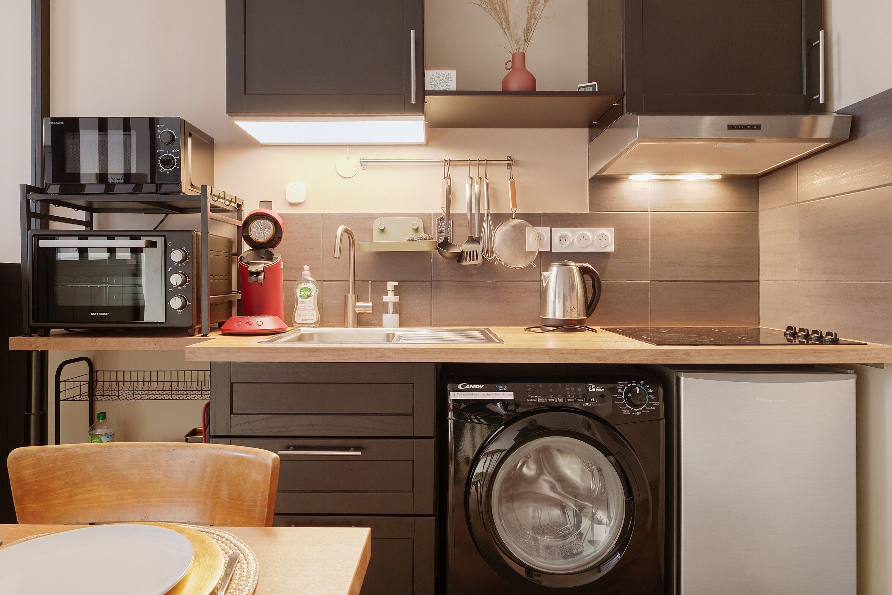 Een kleine keuken met een magnetron, broodrooster, spoelbak en vaatwasser.
