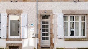 Ein Gebäude mit einer weißen Tür, verriegelten Fenstern und einem Hausnummernschild.