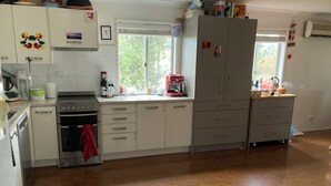 Une cuisine avec des meubles blancs, une cuisinière et une fenêtre.