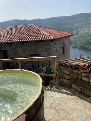 A stone building with a red-tiled roof, a wooden deck, and a hot tub. - Villa in the Ribeira Sacra, O Carocho (Pantón (Lugo))
