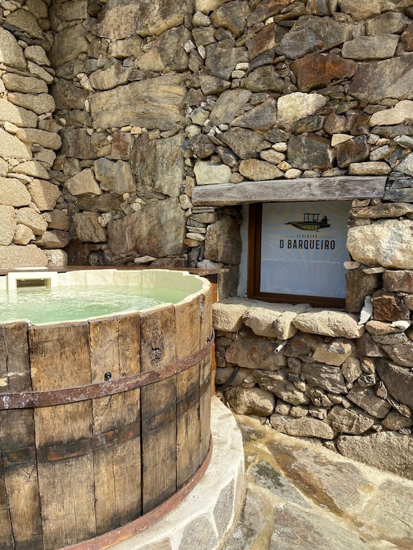 A stone wall with a wooden barrel and a sign reading 'Ecolaguar Orarqueiro'.