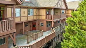 A multi-story building with a balcony, a red door, and a stone foundation. - Cozy Condo with Pools Sauna Golf & Seasonal Hot Tub (Pigeon Forge)