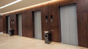 Un espace moderne pour les ascenseurs, avec des panneaux de bois et un revêtement de sol en marbre.