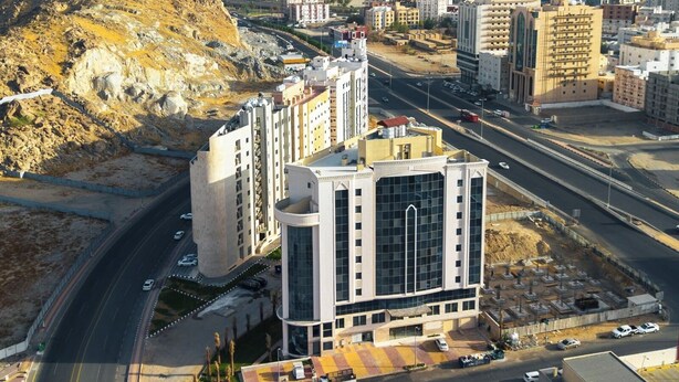 Un quartier urbain moderne, avec un bâtiment remarquable doté d’une grande façade en verre et d’une conception aux lignes courbes.