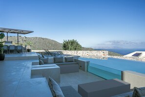 A modern outdoor lounge area with a pool, seating, and a view of the sea. - Luxurious Villa Alea (Rethymno)