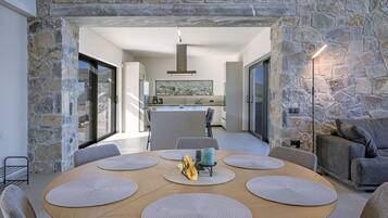 Un comedor moderno con un arco de piedra, una mesa redonda de madera con posavasos y vistas de la cocina y el comedor al fondo.