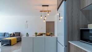 A modern kitchen with a built-in island, a flat-screen TV, and pendant lighting. - Flair 1-BR Apt. & Balcony in Larnaca (Larnaca)