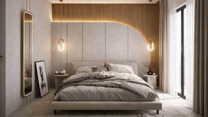 Een moderne slaapkamer met een groot bed, een nachtkastje, een wandlamp en een groot raam met gordijnen.