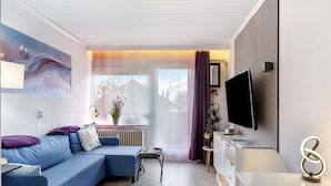 Una sala de estar moderna con un sofá modular, una mesita, un televisor y un elemento decorativo en la pared.
