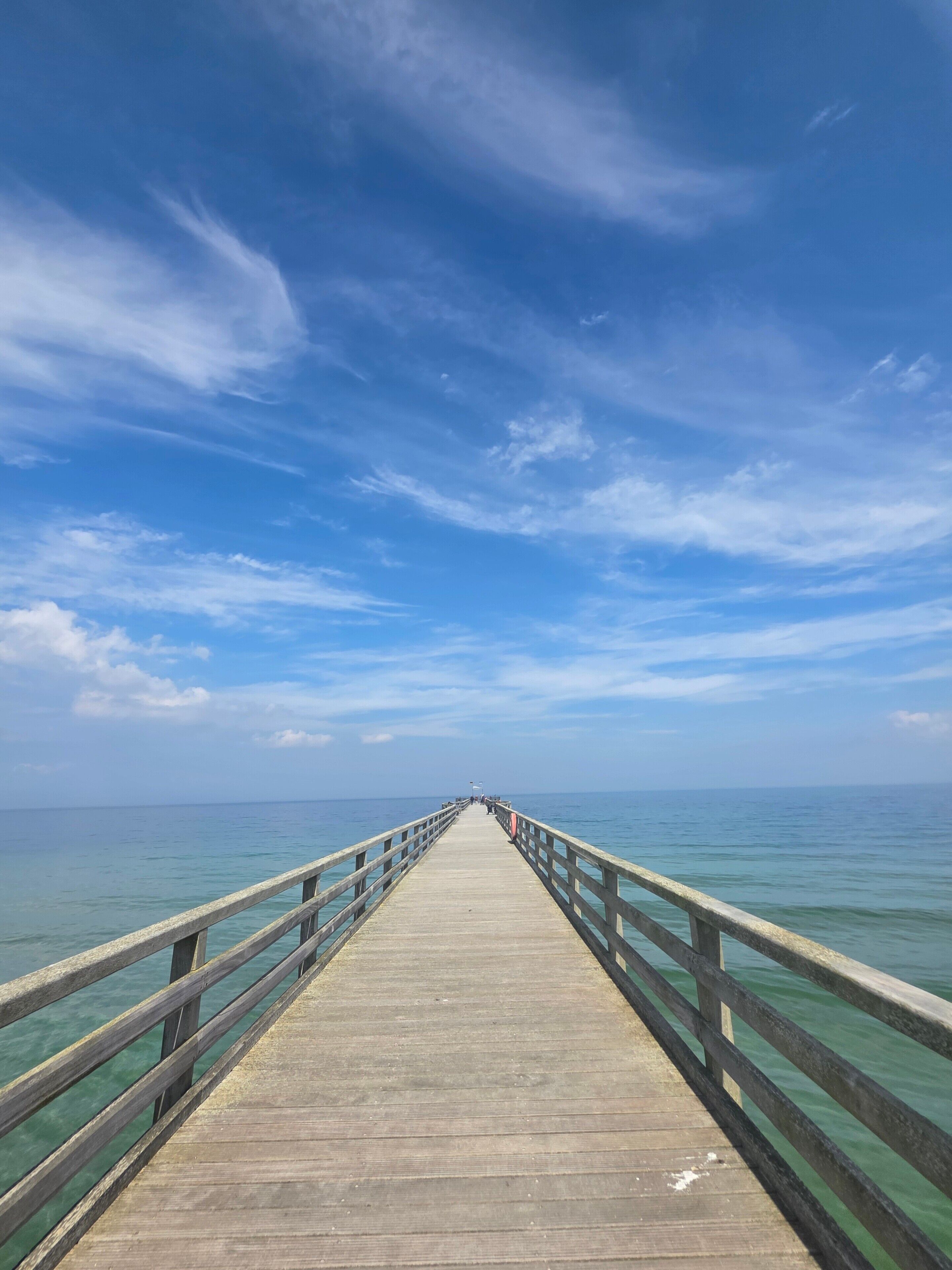 Un muelle de madera que se adentra en aguas tranquilas bajo un cielo despejado.