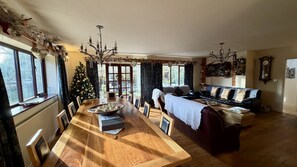 Un salón espacioso con una mesa de comedor de madera, un sofá y un árbol de Navidad.