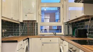 Une cuisine compacte avec des meubles blancs, un lave-linge encastré, un four à micro-ondes et une cuisinière.