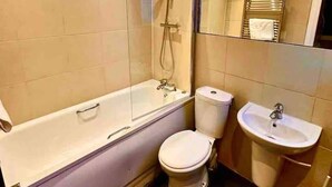 Une salle de bain moderne avec une douche à parois de verre, des toilettes blanches et un lavabo sur colonne.