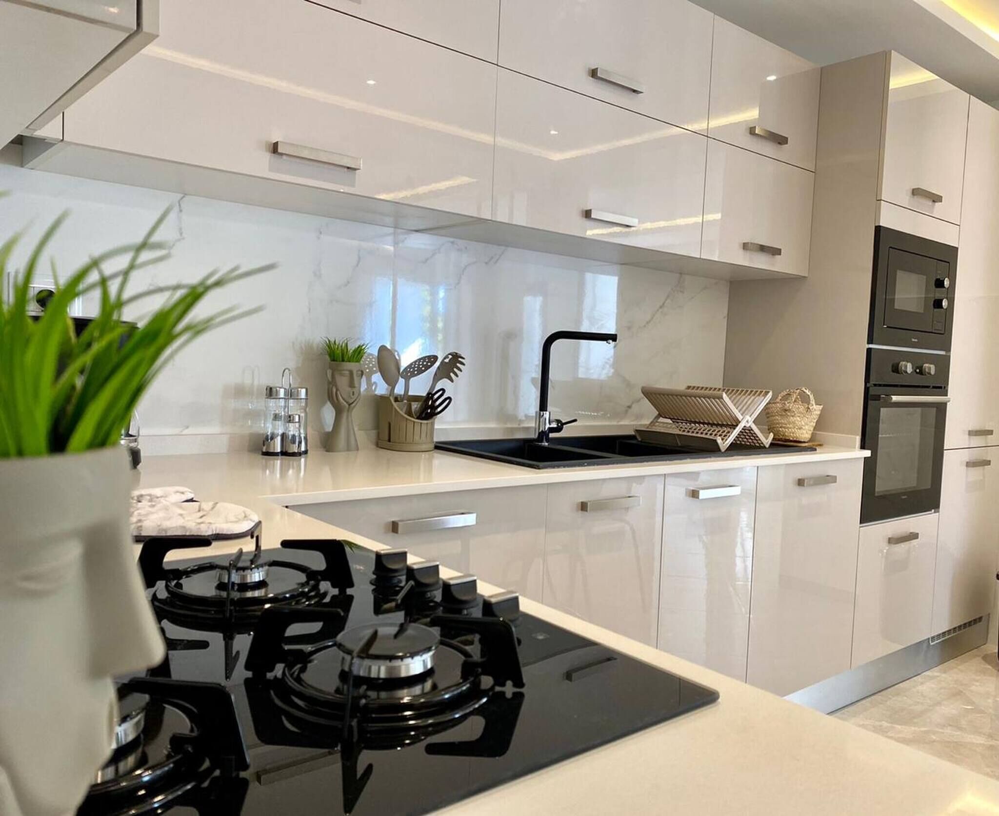 Una cocina moderna con estufa a gas, electrodomésticos de acero inoxidable y armarios blancos.