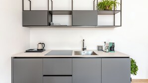 Une cuisine moderne avec des meubles gris, un évier en acier inoxydable et une machine à café.