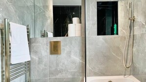 A modern bathroom with a glass-enclosed shower, a white toilet, and a bathtub. - Sunny Neasden Apartment (London)