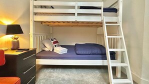 A bunk bed with a ladder, a desk with a lamp, and a chair. - Ground-floor Flat 1 Min to Tube (London)