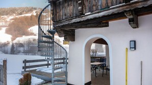 Eine Wendeltreppe führt zu einem Holzbalkon mit Blick auf eine verschneite Landschaft.