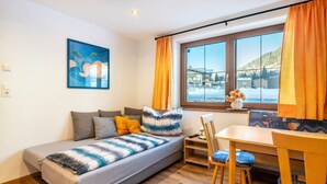 Ein gemütlicher Raum mit Bett, Esstisch und einem fenster mit Vorhängen.
