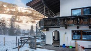 Ein Gebäude mit einem Holzbalkon, einer Wendeltreppe und Blick auf eine verschneite Landschaft.