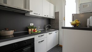 Une cuisine moderne avec des armoires blanches, un plan de travail noir et des appareils en acier inoxydable.