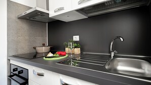Une cuisine moderne avec un plan de travail noir, un évier en acier inoxydable et des armoires blanches.