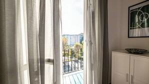 Une pièce avec vue sur un balcon, un meuble blanc et une œuvre d’art abstraite encadrée accrochée au mur.
