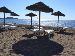 A beach with white lounge chairs and thatched umbrellas. - Charming apartment in San Juan de los Terreros, communal pool access, near beach for 4 people (San Juan de los Terreros)